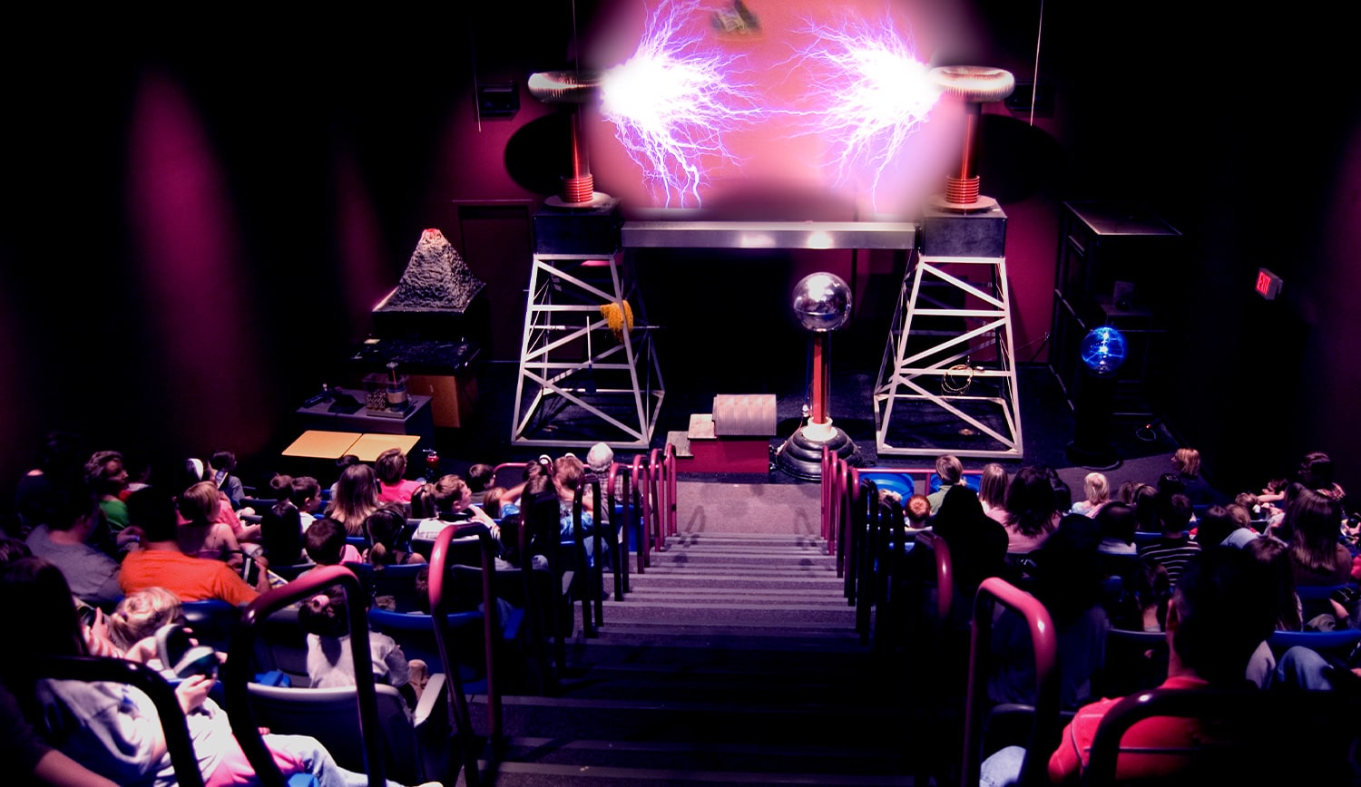 a group of people sitting on a stage with a crowd watching